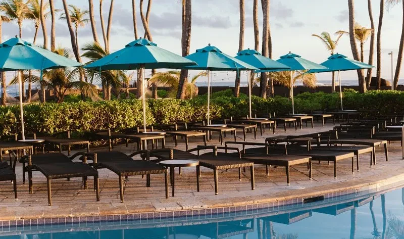 Resort pool deck with lounge furniture and turquoise umbrellas